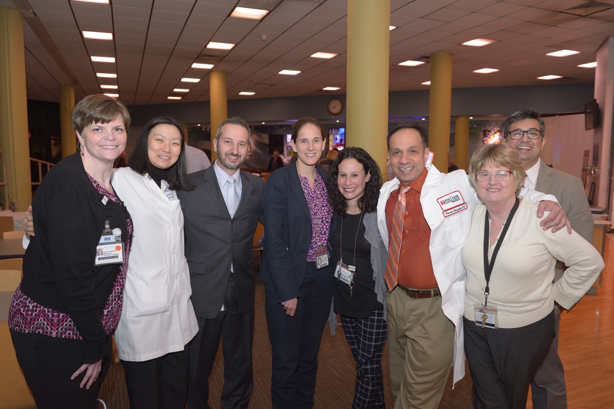 A photograph of a group of medical professionals, including Fox Chase doctors, wrapping their arms around each other and smiling at the camera at an indoor event.